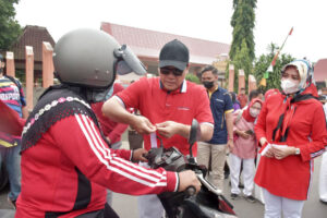 Wahdi dan Qomaru Bagikan Bendera Merah Putih ke Pengendara Jalan
